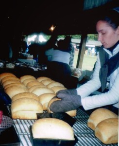 Elissa Orendorf Reigsecker takes loaves out of pans, using oven mitts.
